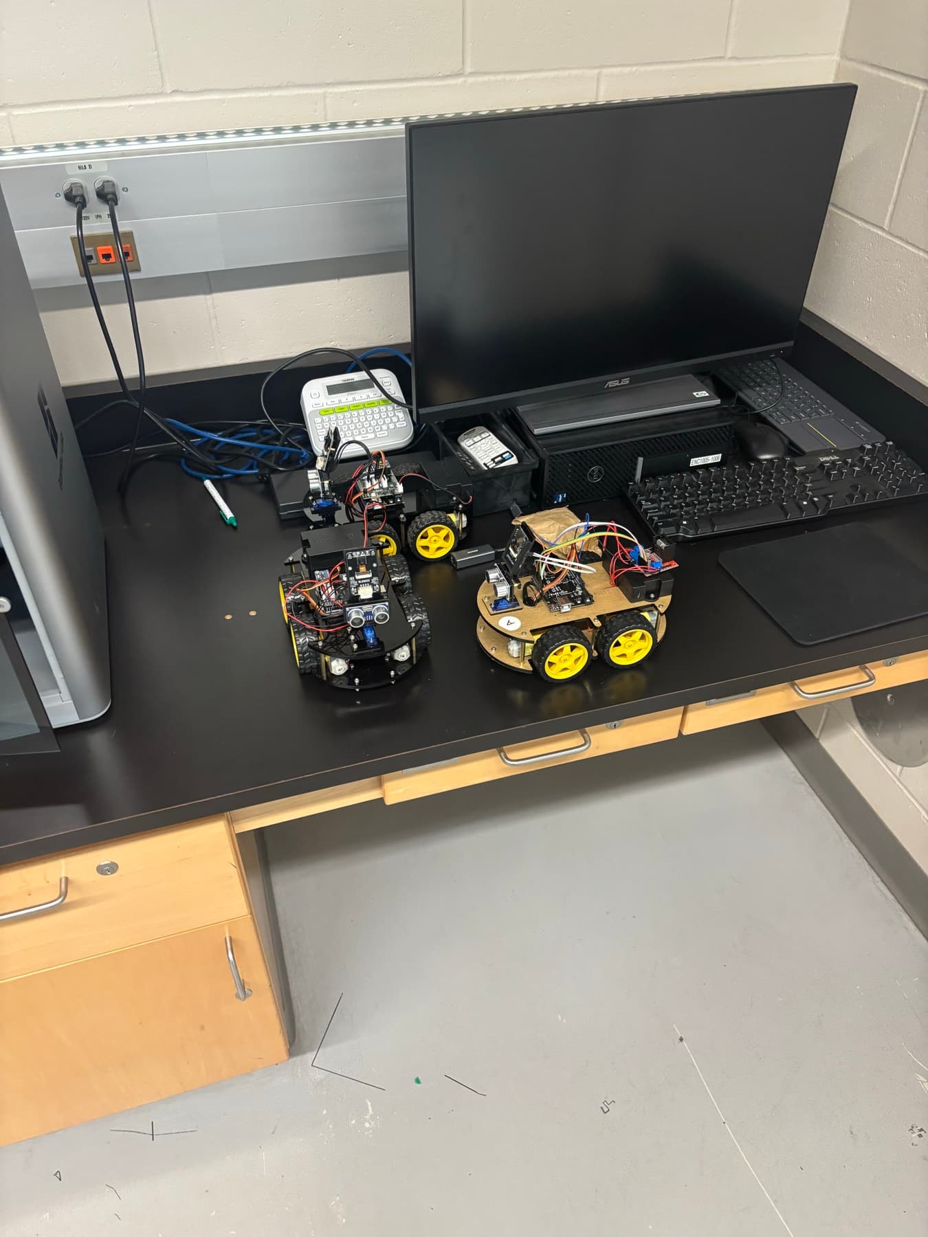 Three small wheeled robot kits on a lab bench